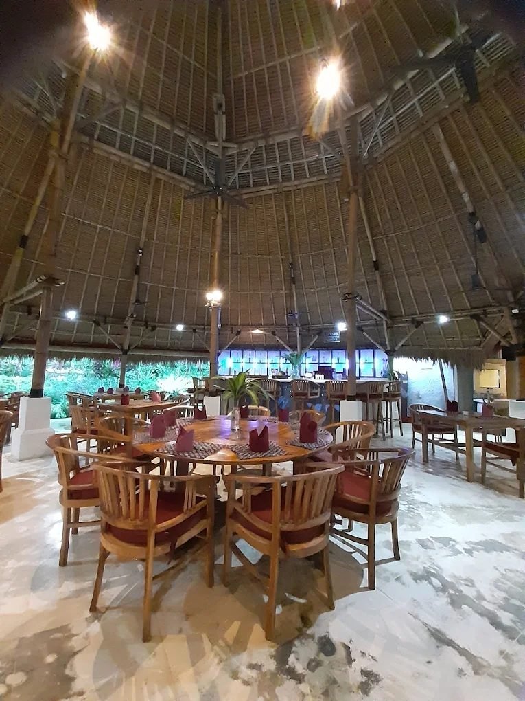 Round dining tables set for service under the thatched roof at The Dining Room Candidasa